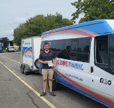 Man holding a certificate next to GS Driver Training vehicle in a training centre, emphasizing professional driving education and CPC compliance.
