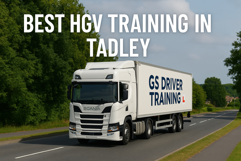 A white Scania HGV training truck with "GS DRIVER TRAINING" branding and a red L plate on the trailer drives down a two-lane road in Tadley. The road is flanked by green trees and grass, with a few suburban houses visible in the background under a partly cloudy sky. Large white text at the top reads "BEST HGV TRAINING IN TADLEY