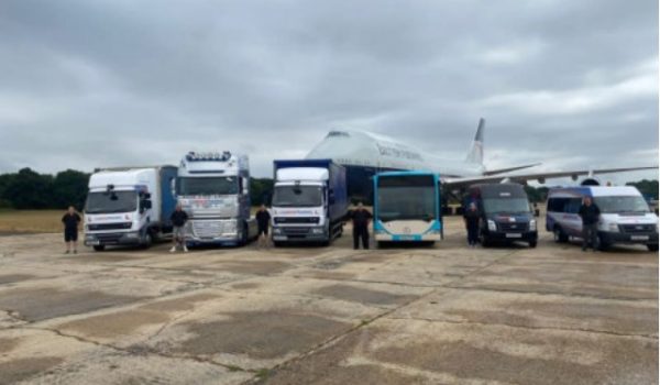 Lineup of various HGV and LGV vehicles, including trucks and a bus, on a training ground with an aircraft in the background, illustrating practical driver training options at GS Driver Training in Reading, Berkshire.